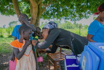 عاملة صحية تقوم بتطعيم فتاة صغيرة في مدرسة ابتدائية في منطقة بوسيا، أوغندا.