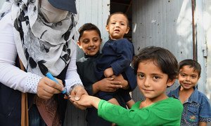 A young girl receives a vaccination against polio from a health worker in Kabul, Afghanistan.