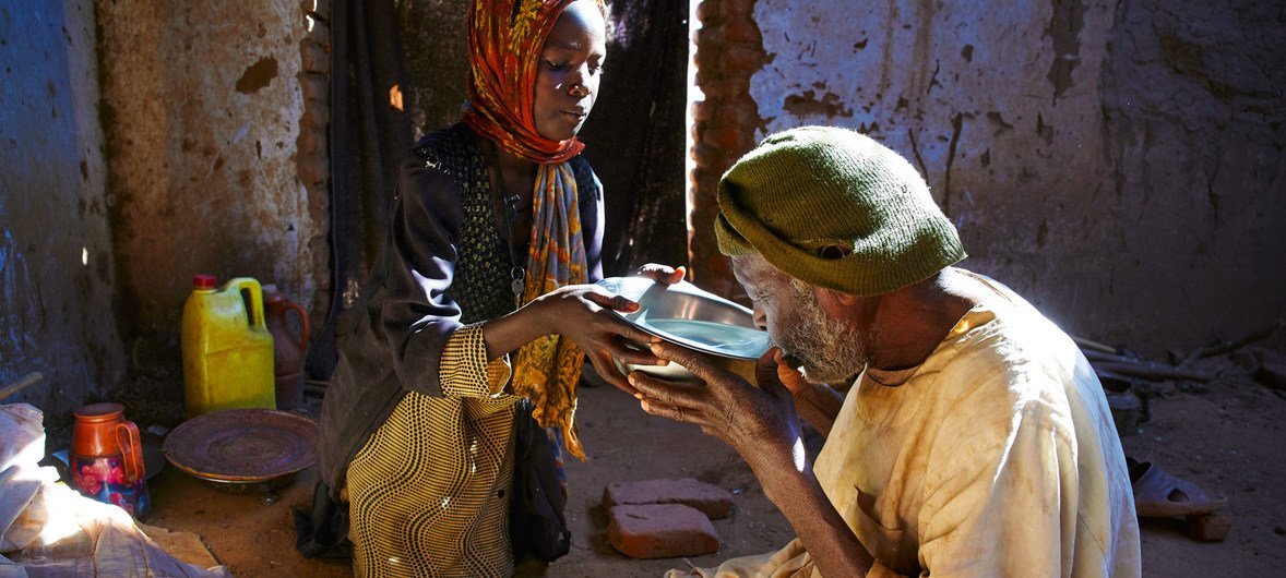 Une fillette de sept ans donne de l'eau à son grand-père pendant qu'il prie dans un camp pour personnes déplacées au Darfour, au Soudan.