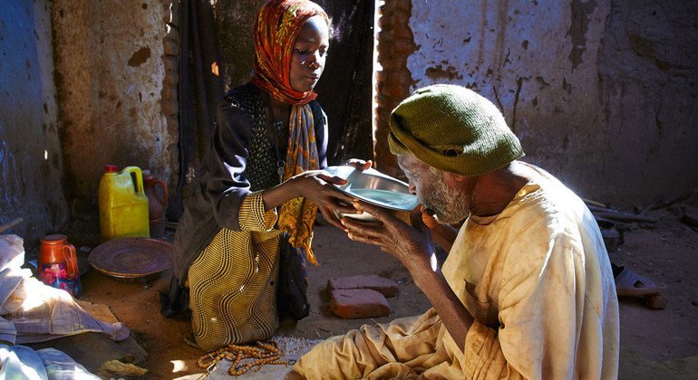 طفلة تقدم الماء لجدها بعد صلاته في مخيم للنازحين في دارفور
