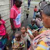 Uma profissional de saúde da República Democrática do Congo com crianças que esperam para receber a vacinação contra o sarampo.