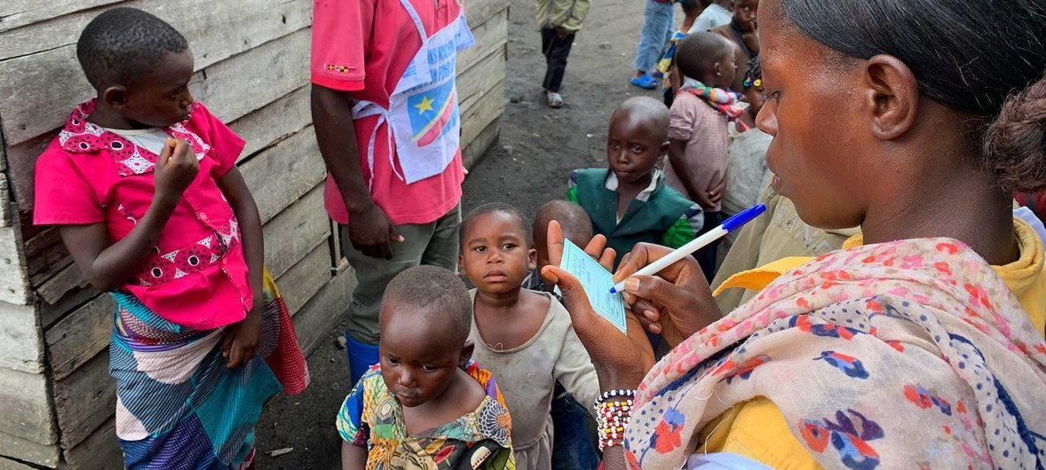 Uma profissional de saúde da República Democrática do Congo com crianças que esperam para receber a vacinação contra o sarampo.