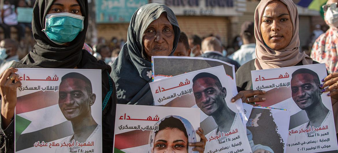 Three women in Khartoum hold pictures of their loved ones who died in protests, in Sudan.