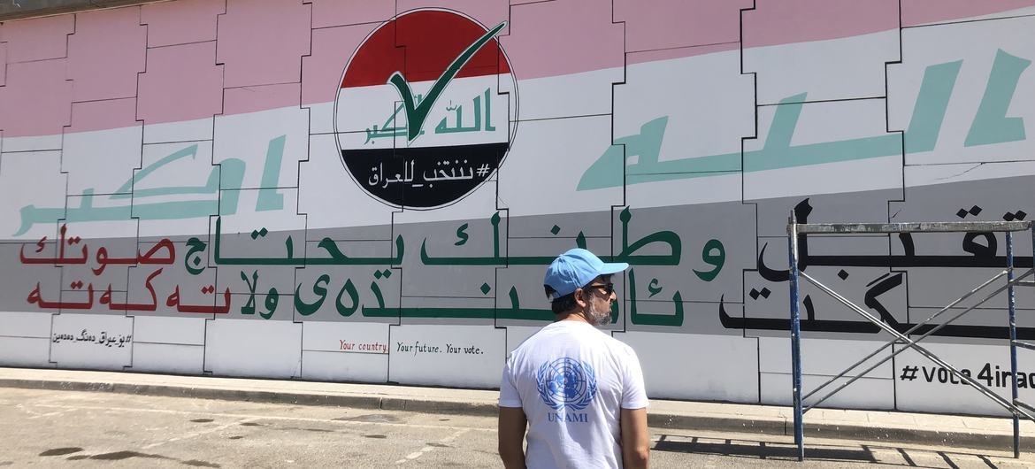 موظف الأمم المتحدة برندن فارما أمام لوحة جدارية بتكليف من بعثة الأمم المتحدة لمساعدة العراق (يونامي) لحث المواطنين العراقيين على التصويت ، 15 سبتمبر 2021.