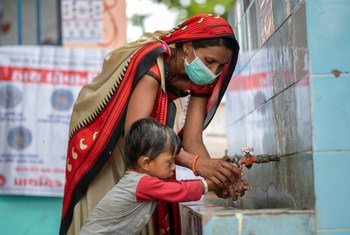 在印度古吉拉特邦，一名社区卫生工作者向一名小男孩展示了如何正确洗手以保持卫生和预防新冠。