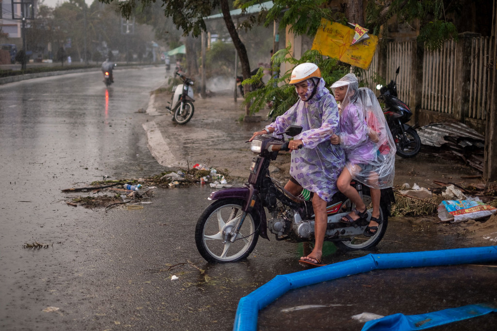 Un hombre lleva a sus hijos en motocicleta por una carretera inundada en la ciudad de Da Nang, en Vietnam, el 30 de octubre de 2020, a raíz del tifón Molave.