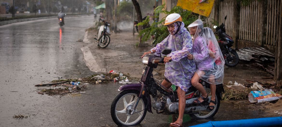 A man carrying his children on a motorbike walks through a flooded road in Da Nang city, Vietnam on October 30, 2020, following Typhoon Molave.