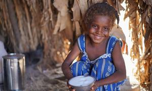 نعمة (7 أعوام) تمسك بطبق فيه سكر وزعه برنامج الأغذية العالمي، في خيمة أسرتها باليمن.