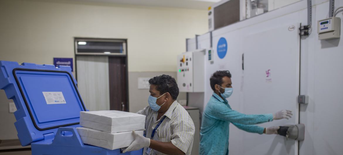 महाराष्ट्र में सरकारी कर्मचारी, ज़िला कोल्ड-चेन केन्द्र पर टीकों के डिब्बे शीतलक यंत्रों में स्थानान्तरित कर रहे हैं.
