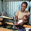 A mother works as a tailor while taking care of her baby in Suba, Kenya.