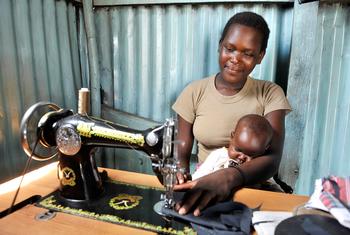 Mulher trabalha como costureira enquanto cuida do filho no Quênia. 