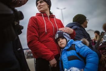 在罗马尼亚的伊萨卡，一位母亲在等待交通工具时安慰她7岁的儿子。