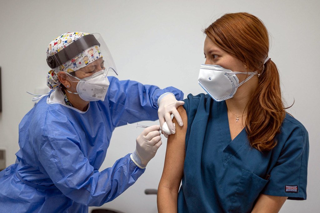 Una sanitaria pone la primera dosis de la vacuna contra el COVID-19 a una paciente en Colombia. 