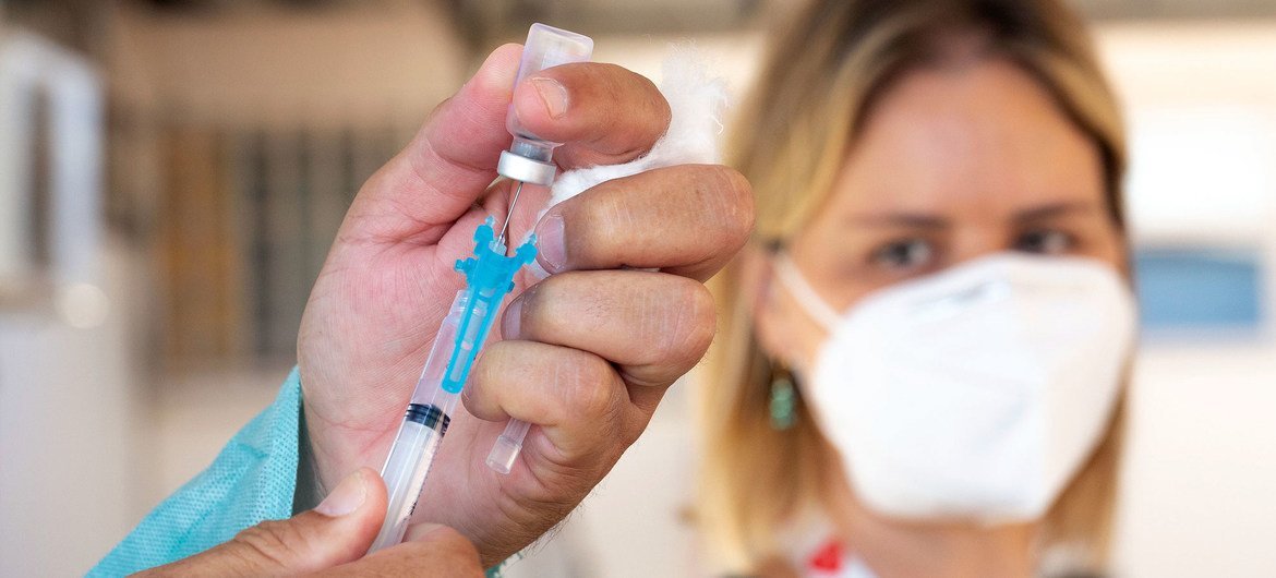 A health care worker prepares to administer a COVID-19 vaccine in Brazil.