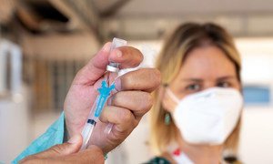 A health care worker prepares to administer a COVID-19 vaccine in Brazil.