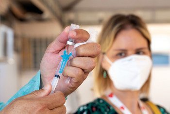 A health care worker prepares to administer a COVID-19 vaccine in Brazil.