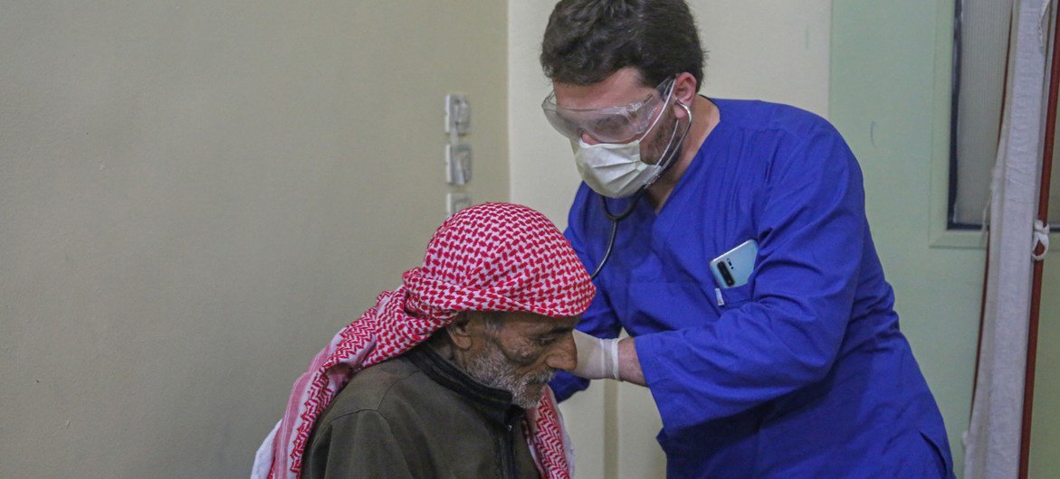 सीरिया में युद्ध के कारण विस्थापित एक व्यक्ति की स्वास्थ्य जाँच-पड़ताल करते हुए एक एक डॉक्टर.