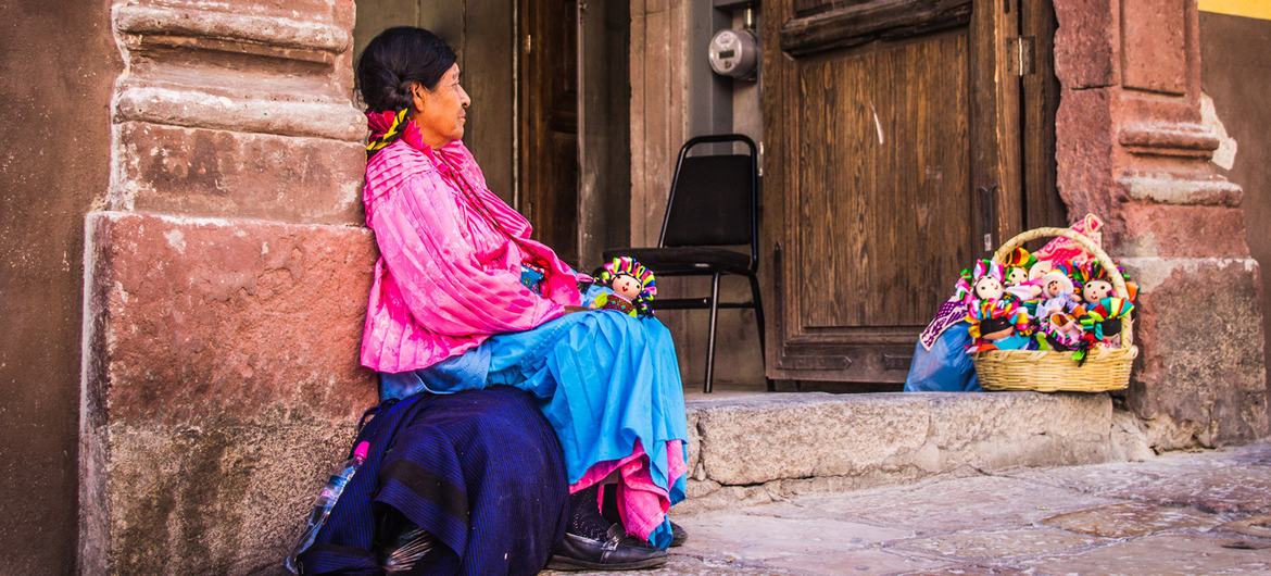 मैक्सिको के सैंटियागो डी क्वेरेटारो की गलियों में गुड़िया बेचती, मैक्सिको के आदिवासी समूह की एक महिला.