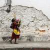 Una mujer carga una cesta de flores por las calles empedradas y los muros derruidos de Antigua, en Guatemala.