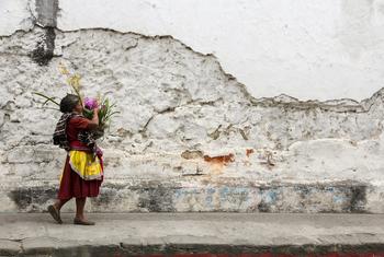 Una mujer carga una cesta de flores por las calles empedradas y los muros derruidos de Antigua, en Guatemala.