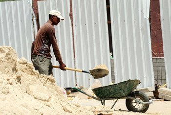 A laborer shoveling sand at a construction site..
