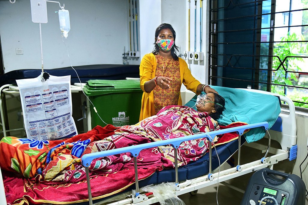 Mgonjwa wa ugonjwa wa COVID-19 akihudumiwa na mwanae wa kike katika hospitali jimbo la Bengal magharibi, India.