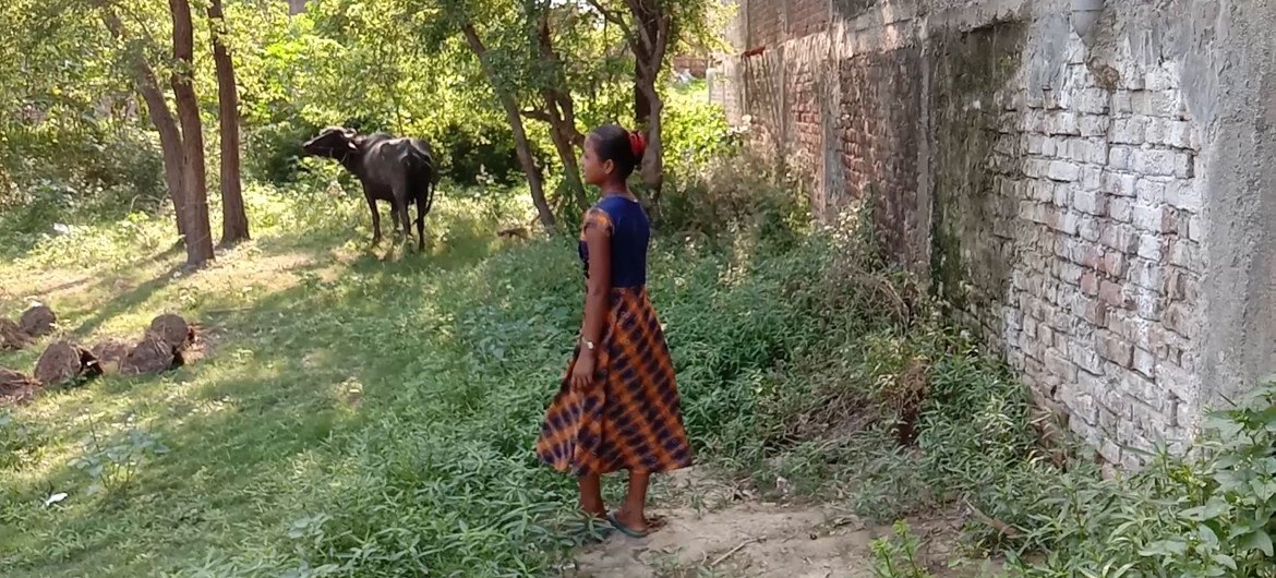 尼泊尔13岁的女孩玛杜在自家后院，身后是家中养的牛。