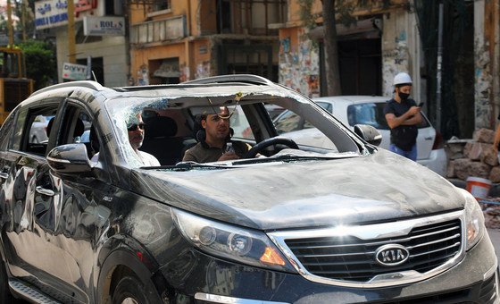 Men drive a windshieldless car after an explosion in Beirut damaged the vehicle on Tuesday.