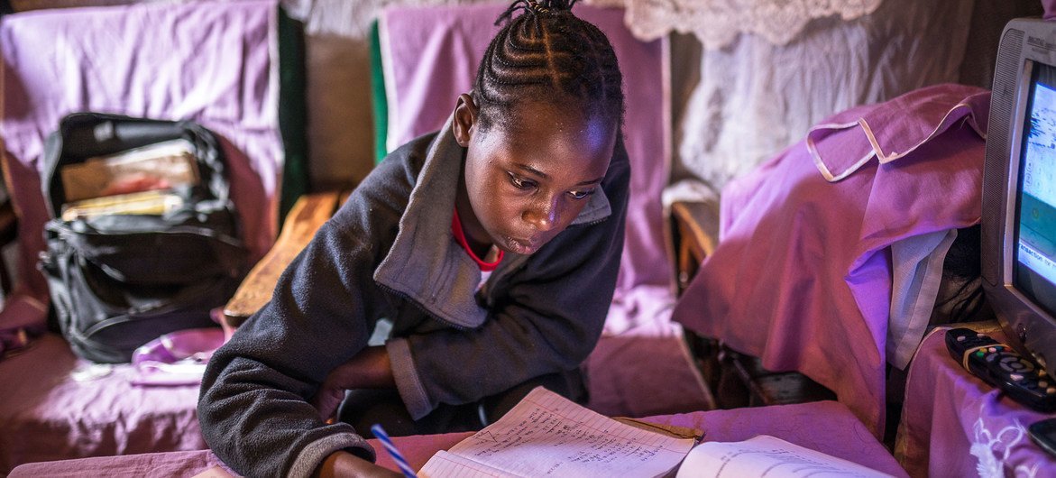 एक केनयाई लड़की, नैरोबी स्थित अपने घर में, कोविड-19 महामिारी के दौरान पढ़ाई करते हुए.