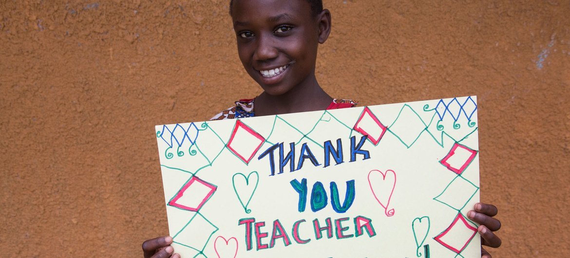 Una niña ugandesa de 12 años muestra un mensaje de agradecimiento a su maestro durante la pandemia de COVID-19.