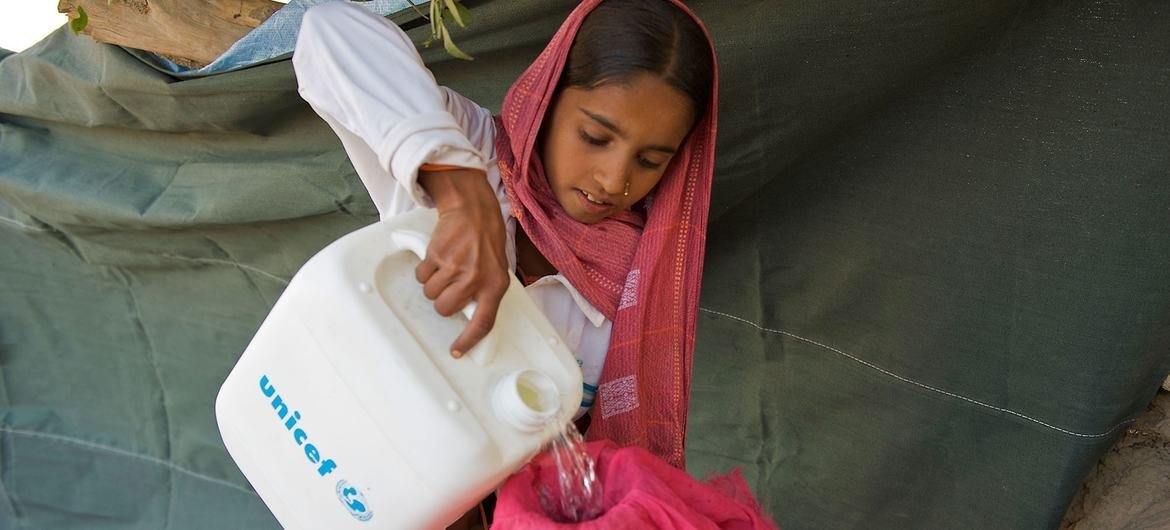 Una niña vacía el agua recolectada del lecho de un río en una aldea afectada por las inundaciones en Pakistán.  (expediente)