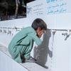 طفل صغير يرتدي شلوار قميص أخضر اللون يغسل وجهه عند نقطة مياه قامت UNICEF بتركيبها في مستشفى في هرات.