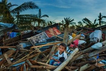 菲律宾普罗克区，一个男孩坐在被台风雷摧毁的房屋废墟中。