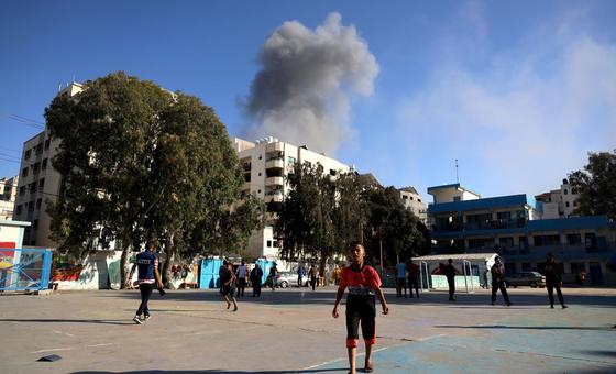 Children play football while an explosion occurs nearby, in the Gaza Strip, Palestine.