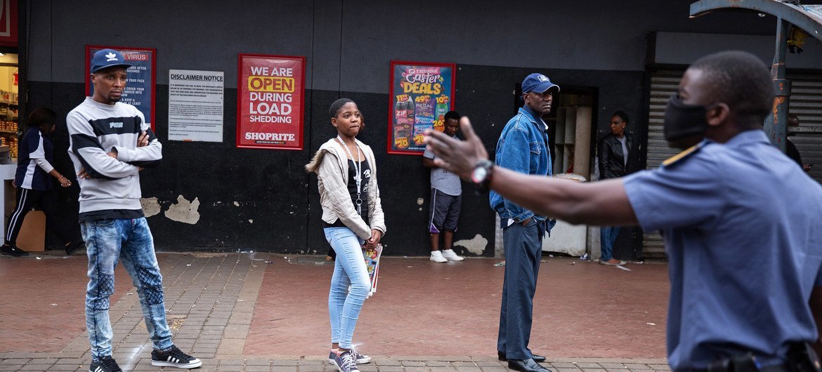 Police order shoppers queueing up outside a shop to maintain a safe distance from each other in Hillbrow, Johannesburg, South Africa, 30 March 2020