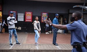 南非约翰内斯堡，警察提醒商店外排队的顾客保持社交距离。(2020年3月30日)