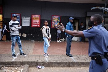 Police order shoppers queueing up outside a shop to maintain a safe distance from each other in Hillbrow, Johannesburg, South Africa, 30 March 2020