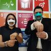 Os surdos Rafael Salafranca e Adriana Gutiérrez Cirlos demonstram a palavra "inclusão" em Língua Gestual Mexicana enquanto usam máscaras faciais inclusivas em frente a um painel com os Objetivos de Desenvolvimento Sustentável.