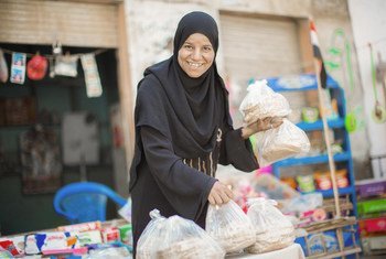 Sayyida empile des galettes de pain frais devant son magasin. 