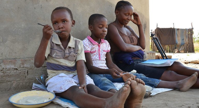 Una madre ayuda a sus hijos a estudiar en Zimbabwe durante la pandemia