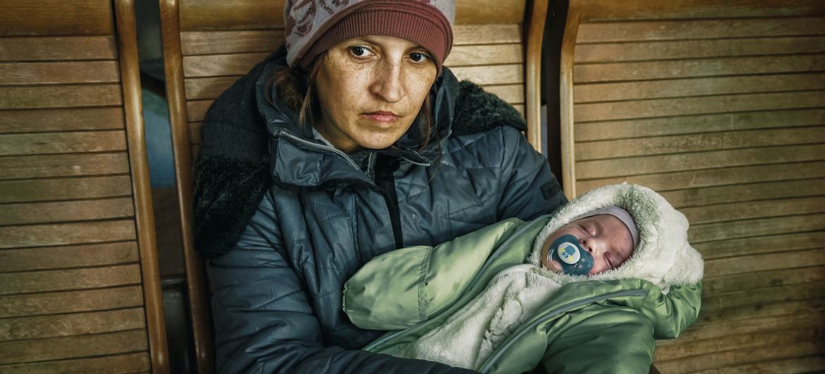 Lyuba, con su hijo de dos meses en brazos, espera sentada en una estación de tren en Uzhhorod, tras haber huir del conflicto en Ucrania.