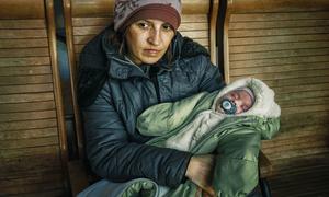 Lyuba with her two-month-old child sits in a train station in Uzhhorod after fleeing conflict in Ukraine.