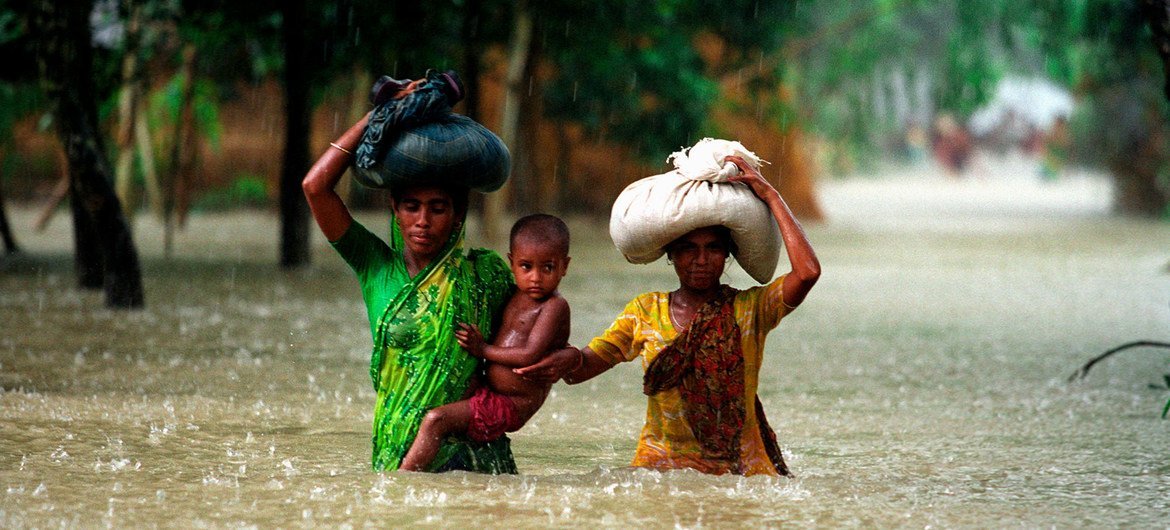 People wade through water during floods in the Kurigram district of Bangladesh.