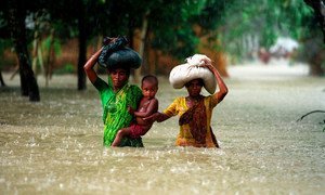 People wade through water during floods in the Kurigram district of Bangladesh.
