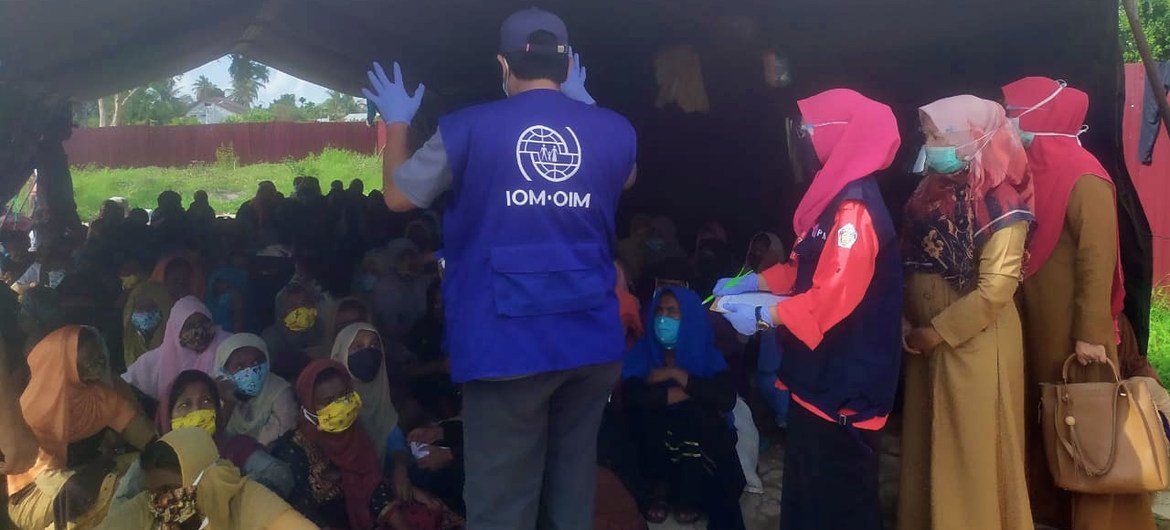 Funcionário da OIM ajudando refugiados na chegada à Indonésia