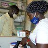 在新冠大流行期间，一名感染艾滋病毒的妇女在乌干达的一个健康中心取药。