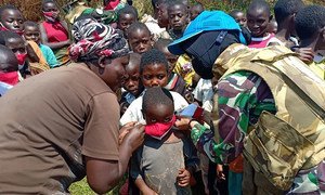 काँगो लोकतांत्रिक गणराज्य के एक गाँव में एक महिला यूएन शान्तिरक्षक, फ़ेस मास्क वितरित कर रही है.