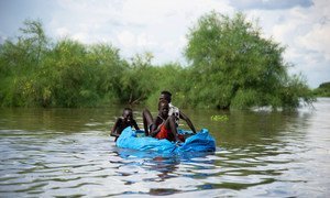 Children create their own boat using tarpaulin and plastic bottles during heavy flooding in South Sudan.