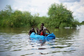 Children create their own boat using tarpaulin and plastic bottles during heavy flooding in South Sudan.