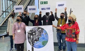 A group armed with signs pose for photographers at the main corridor of the Blue Zone at the COP26 Climate Conference in Glasgow, Scotland.